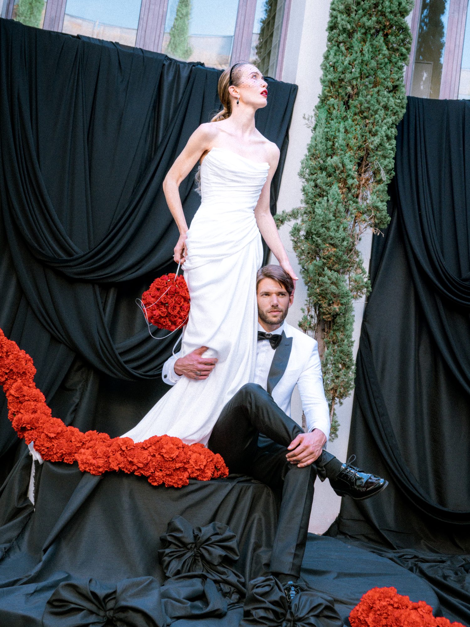 Pareja de novios entre flores rojas y telas negras
