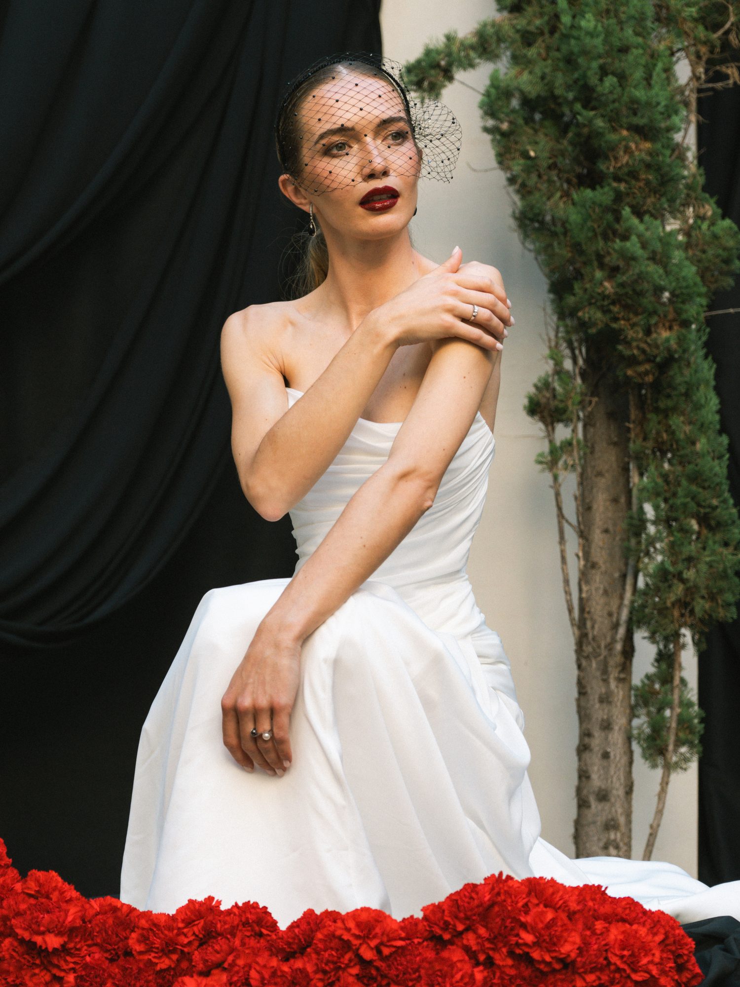 Novia sentada entre flores rojas